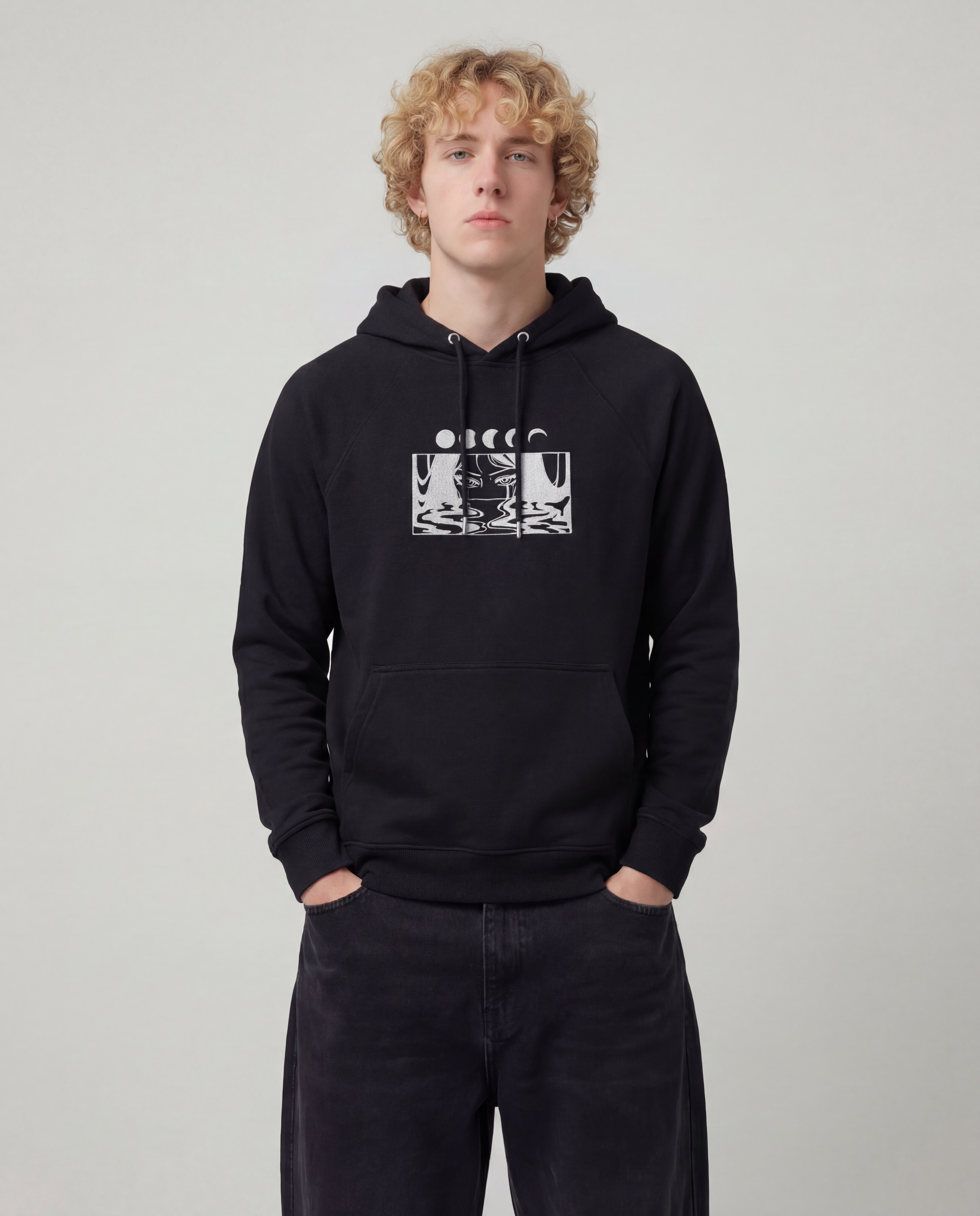 wearing_a_cotton_heritage_hoodie_Model_wearing_baggy_dark_black_jeans_with_a_light_grey_think_hoodie_on_the_front_graphic_is_embroirdered._the_hoodie_is_black.png